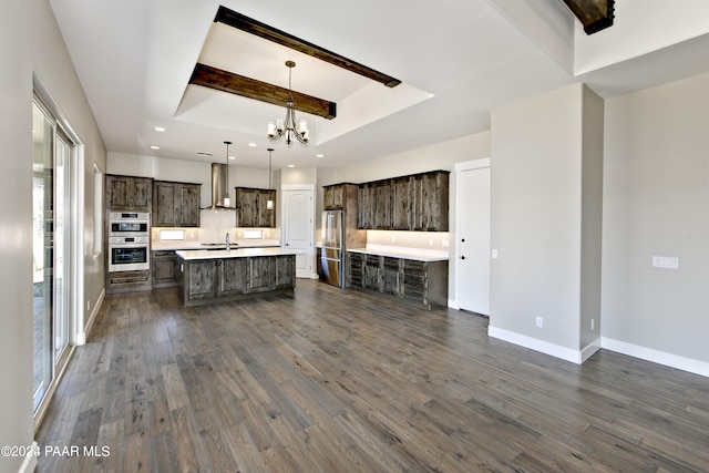 kitchen featuring wall chimney exhaust hood, dark brown cabinetry, light countertops, and a raised ceiling