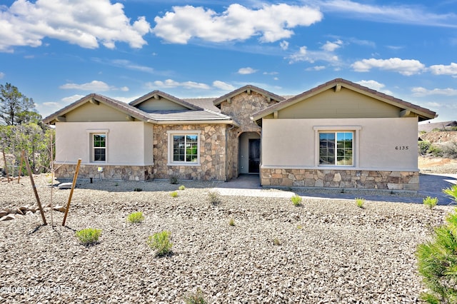ranch-style house featuring a tile roof and stone siding
