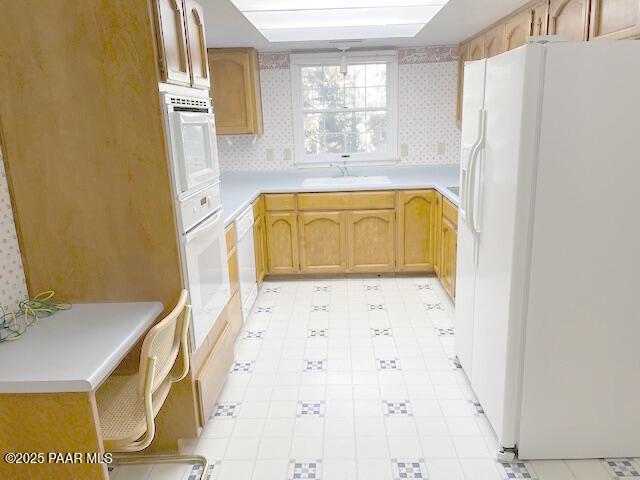 kitchen featuring backsplash, white appliances, sink, and light brown cabinetry