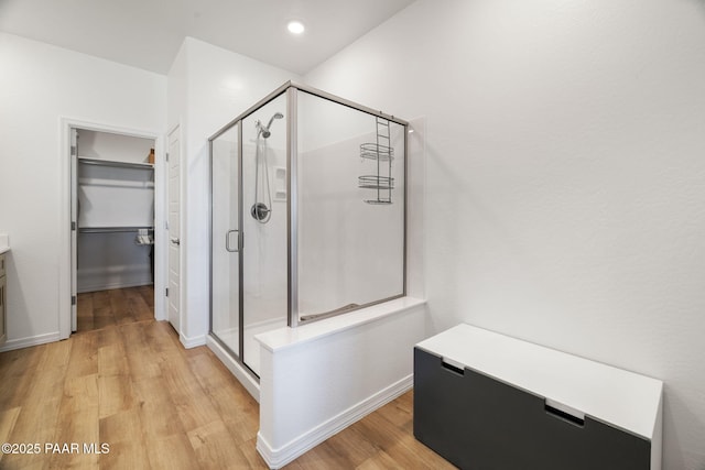 bathroom with a walk in closet, recessed lighting, a shower stall, vanity, and wood finished floors