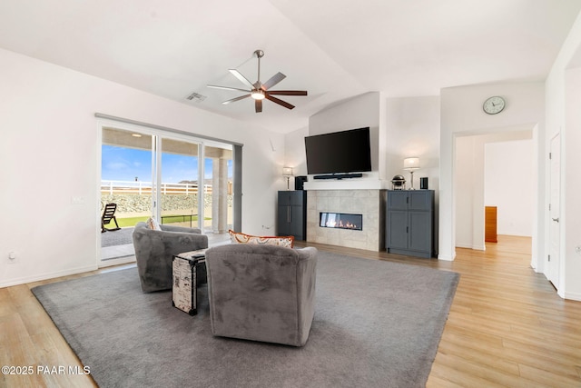 living room featuring a fireplace, lofted ceiling, visible vents, light wood-style flooring, and ceiling fan
