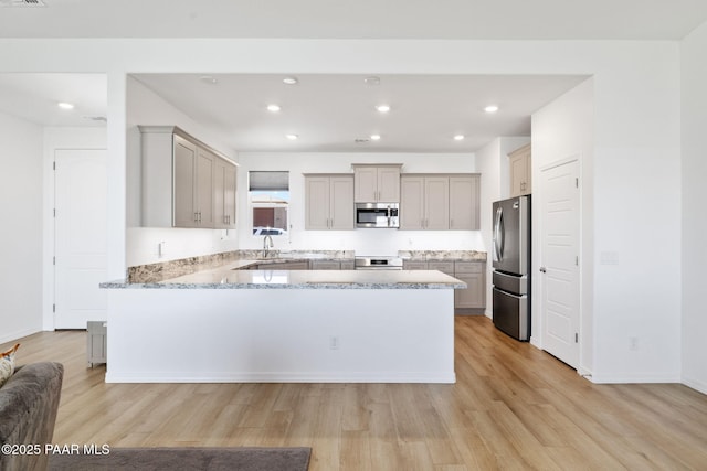 kitchen featuring a peninsula, light wood-style flooring, appliances with stainless steel finishes, and recessed lighting
