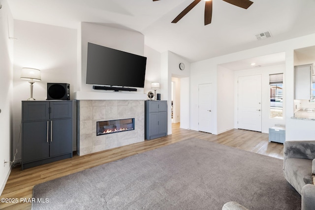 carpeted living room featuring lofted ceiling, visible vents, a fireplace, and wood finished floors
