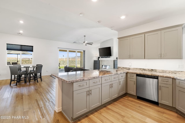 kitchen featuring light wood finished floors, dishwasher, light stone counters, a peninsula, and gray cabinets