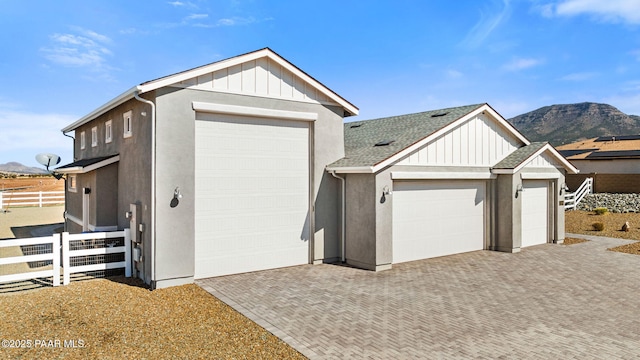exterior space with decorative driveway, a mountain view, and fence