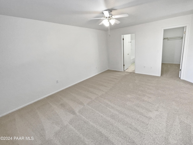 unfurnished bedroom featuring a walk in closet, ceiling fan, connected bathroom, light colored carpet, and a closet