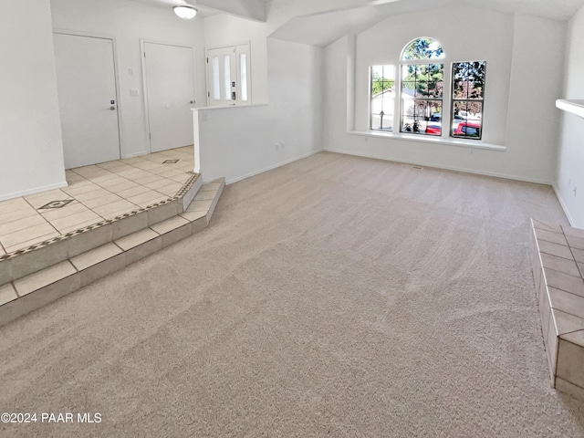 unfurnished living room featuring light carpet and vaulted ceiling