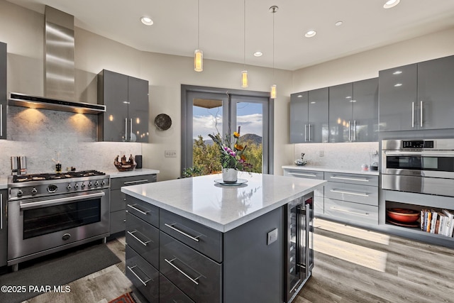 kitchen featuring gray cabinetry, wall chimney range hood, and stainless steel appliances