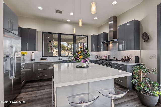 kitchen with backsplash, stainless steel appliances, wall chimney range hood, pendant lighting, and a kitchen island