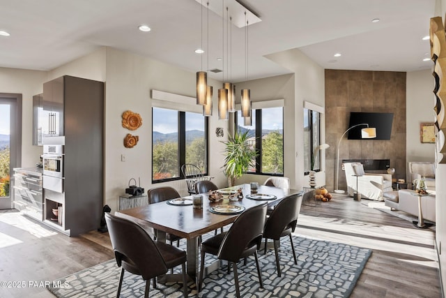 dining space featuring a large fireplace, an inviting chandelier, and light hardwood / wood-style flooring