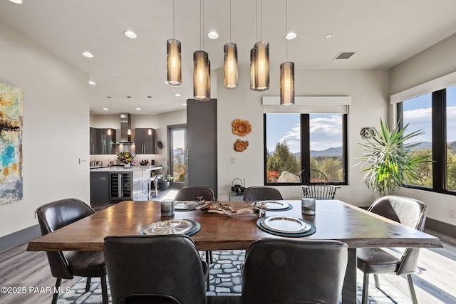 dining room featuring wine cooler, a healthy amount of sunlight, and light hardwood / wood-style floors