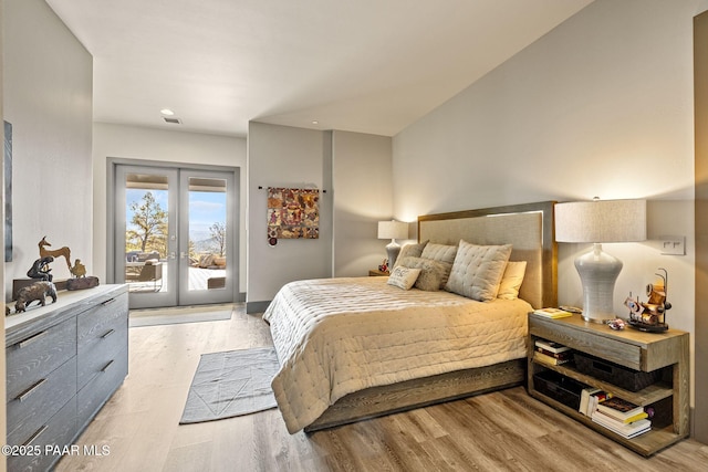 bedroom featuring access to exterior, light hardwood / wood-style flooring, and french doors