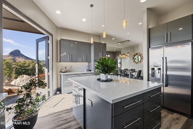 kitchen featuring pendant lighting, a mountain view, stainless steel built in fridge, gray cabinets, and a kitchen island