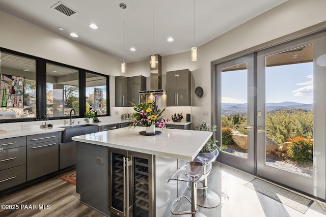 kitchen featuring island exhaust hood, a kitchen island, a mountain view, wine cooler, and hanging light fixtures