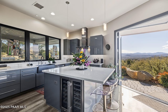 kitchen with decorative light fixtures, a mountain view, a center island, wine cooler, and range hood