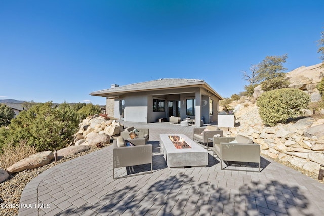 rear view of property with a patio area and an outdoor living space with a fire pit