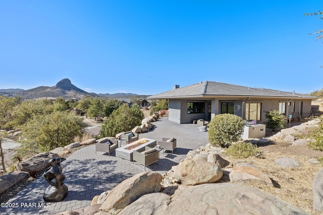 rear view of house featuring a mountain view, a patio area, and an outdoor living space with a fire pit