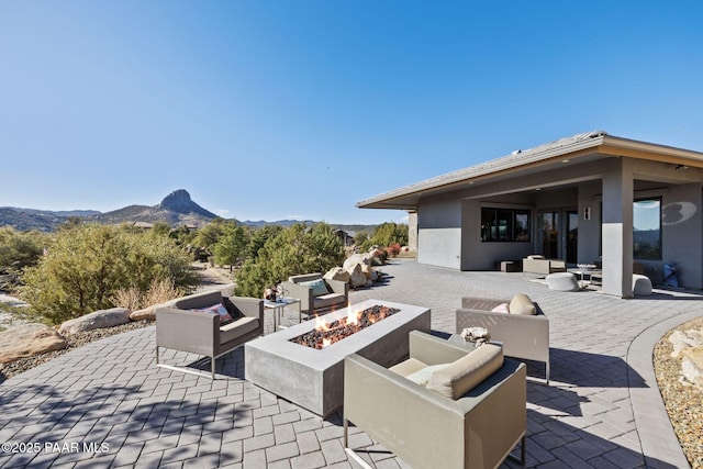 view of patio featuring a mountain view and an outdoor living space with a fire pit