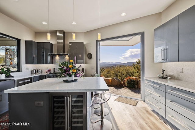 kitchen with wall chimney range hood, pendant lighting, a mountain view, a center island, and plenty of natural light