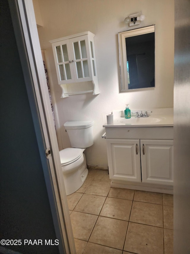 half bath featuring toilet, vanity, and tile patterned floors