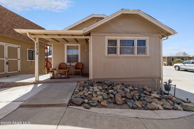 back of house featuring covered porch and a shingled roof