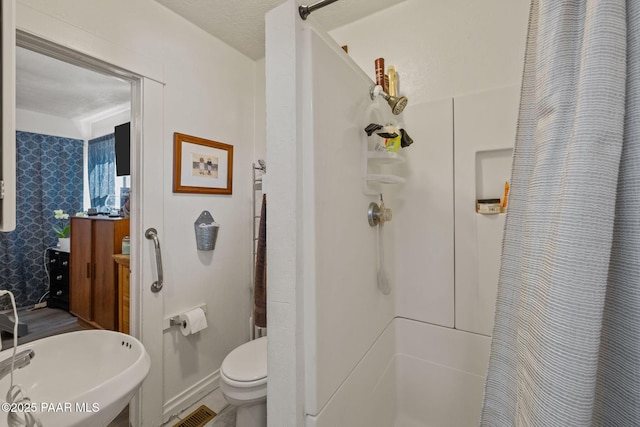 bathroom with curtained shower and toilet