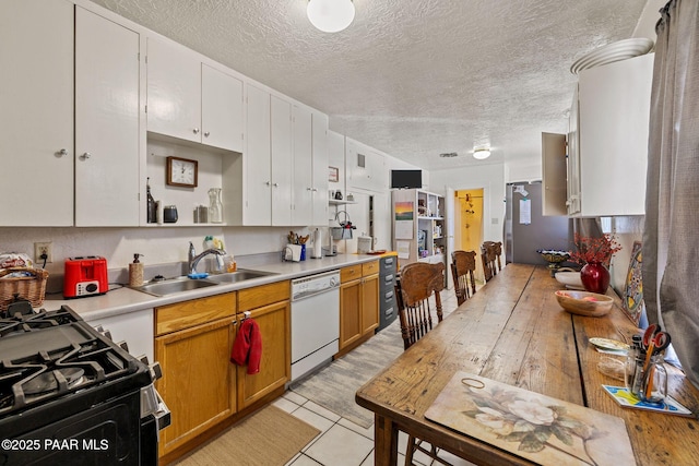 kitchen featuring dishwasher, light countertops, range with gas stovetop, a textured ceiling, and a sink