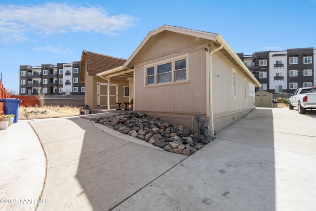 view of side of home featuring a storage shed, an outdoor structure, and roof with shingles