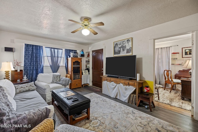 living room featuring ceiling fan, a textured ceiling, and wood finished floors