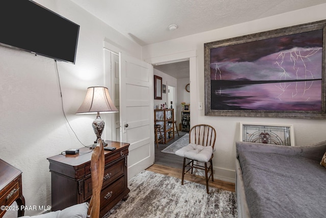 living area with baseboards, a textured ceiling, and wood finished floors