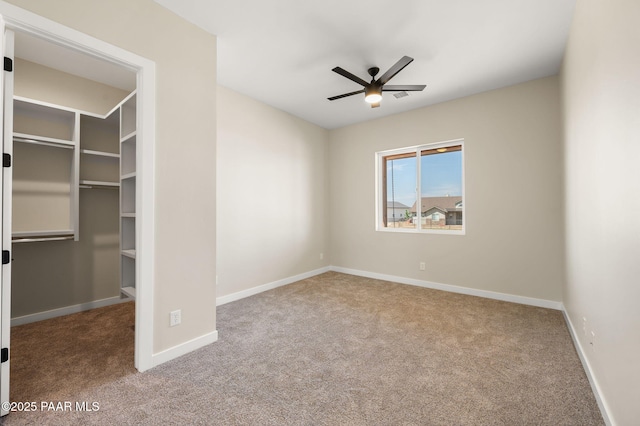 unfurnished bedroom featuring a spacious closet, carpet floors, and baseboards