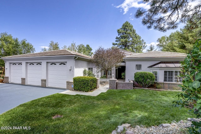 single story home featuring brick siding, stucco siding, an attached garage, a front yard, and driveway