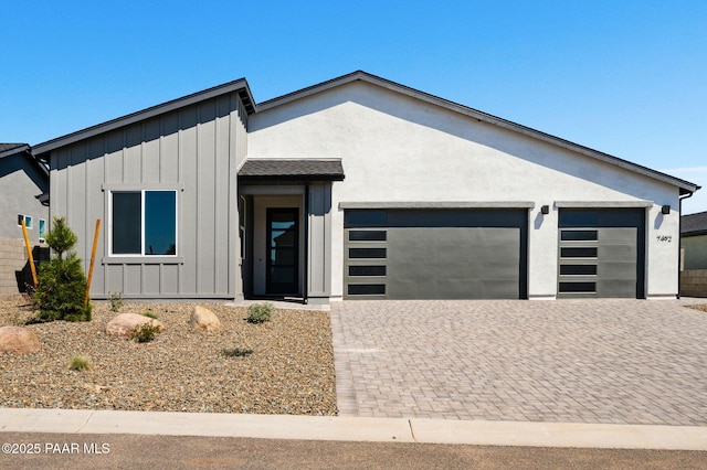 7492 E Louie Ln, Prescott Valley, AZ 86315 - view of front of house featuring board and batten siding, decorative driveway, a garage, and stucco siding
