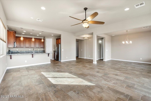 unfurnished living room featuring sink and ceiling fan with notable chandelier