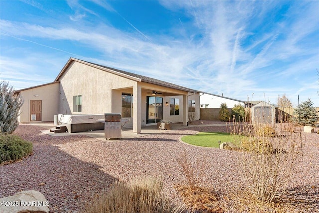 rear view of property featuring a hot tub, a patio, and ceiling fan