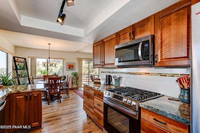 930 Ohio St, Prescott, AZ 86303 - kitchen with stainless steel appliances, a tray ceiling, light wood-type flooring, decorative backsplash, and light stone countertops