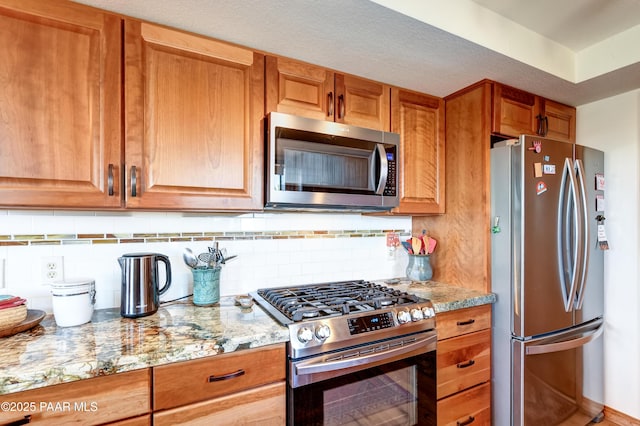 930 Ohio St, Prescott, AZ 86303 - kitchen with appliances with stainless steel finishes, light stone counters, tasteful backsplash, and brown cabinetry