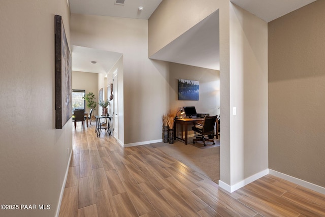 hall featuring a towering ceiling and hardwood / wood-style floors