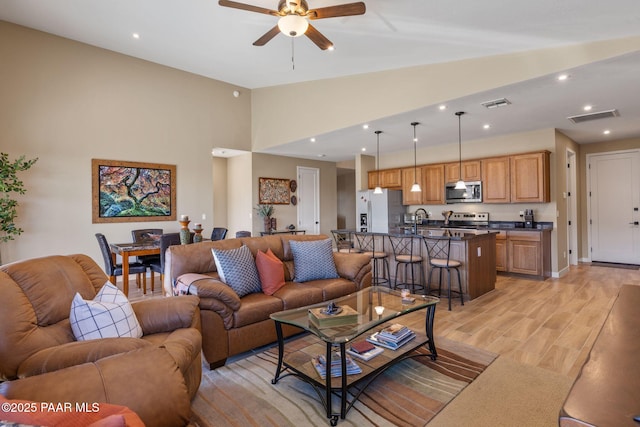 living room featuring vaulted ceiling, sink, ceiling fan, and light hardwood / wood-style flooring