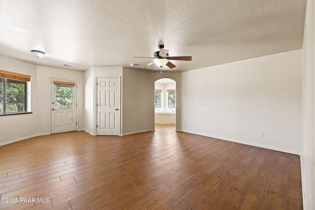 25870 N Merlot Ln, Paulden, AZ 86334 - spare room featuring a ceiling fan, wood finished floors, arched walkways, baseboards, and a textured ceiling