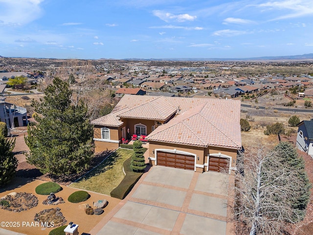 view of front of home featuring a tiled roof, an attached garage, concrete driveway, a residential view, and stucco siding