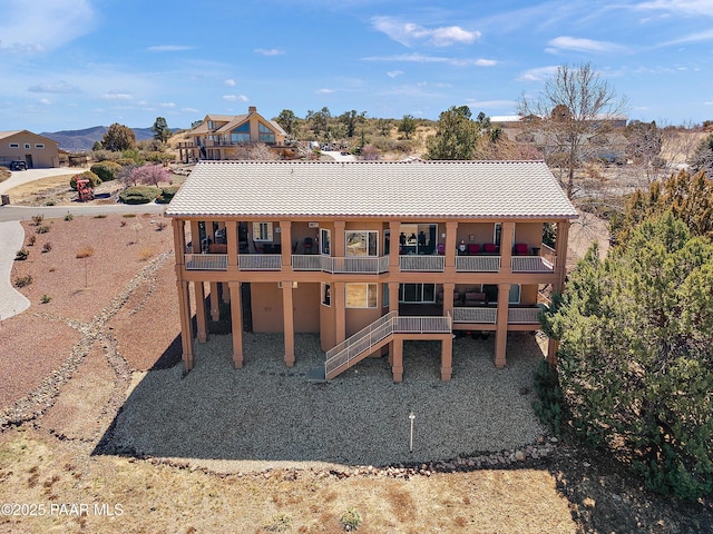 rear view of property featuring stucco siding, a tiled roof, and a balcony