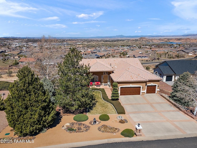 view of front of house featuring concrete driveway, stucco siding, a tiled roof, a residential view, and a garage