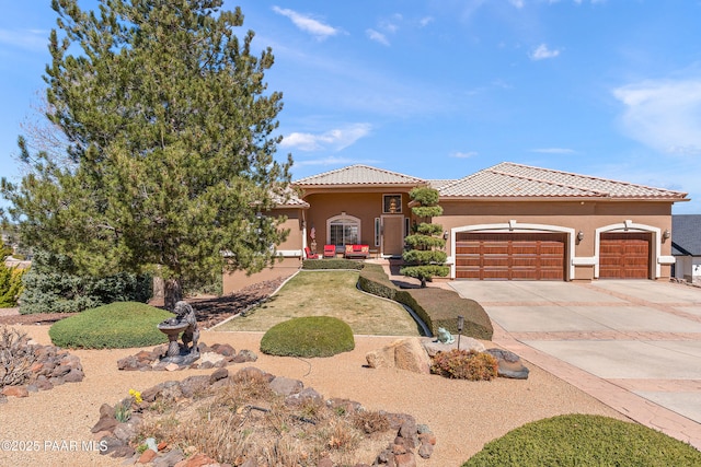 view of front of property with a tile roof, stucco siding, an attached garage, and concrete driveway