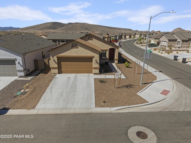 view of front of property featuring a residential view, stucco siding, a mountain view, concrete driveway, and an attached garage