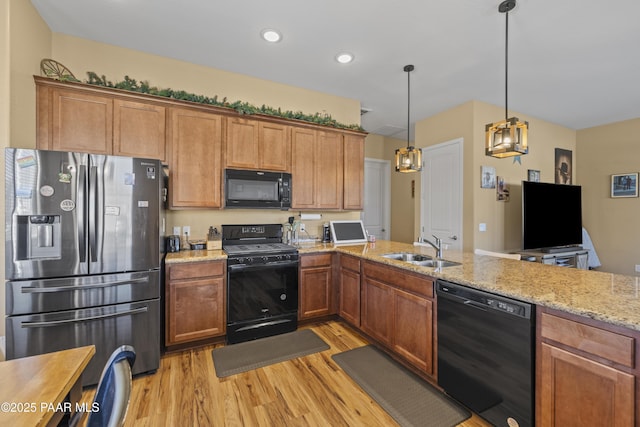 kitchen featuring light stone countertops, a sink, brown cabinetry, black appliances, and light wood-style flooring