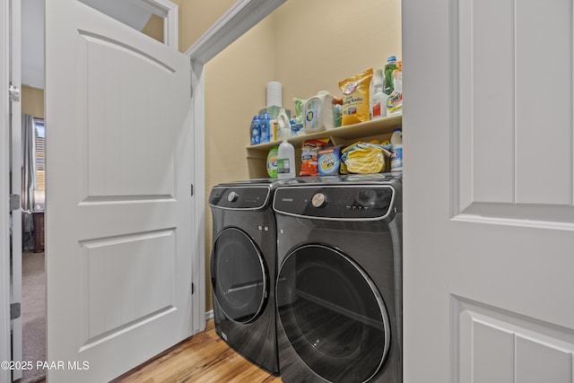 clothes washing area featuring washer and clothes dryer, laundry area, and light wood finished floors
