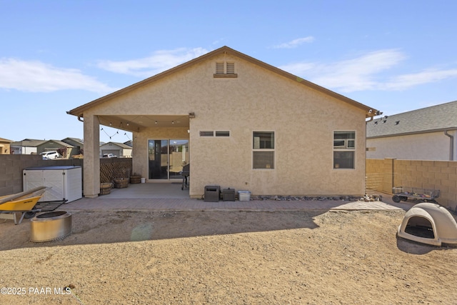 rear view of house with stucco siding, a patio area, and a fenced backyard
