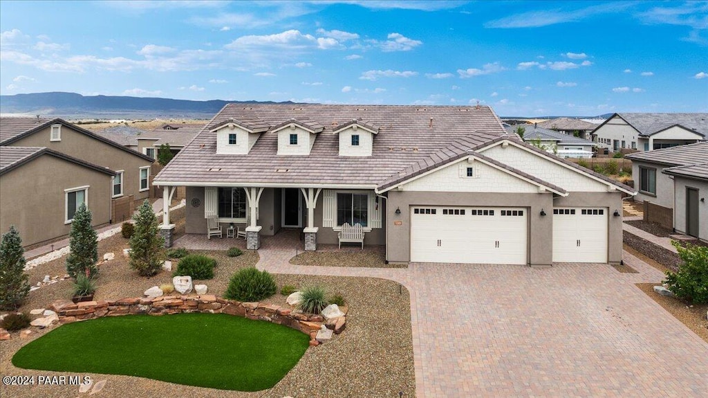 view of front of house featuring covered porch, a mountain view, a garage, and a front yard