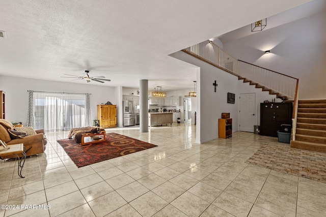 living room featuring ceiling fan, light tile patterned floors, and a textured ceiling